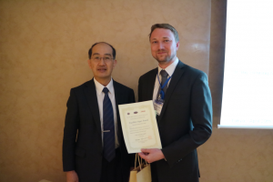 Prof. Masanori Kunieda, chairman der ISEM-XVIII Konferenz, überreicht den Excellent Paper Award an Dr. Henning Zeidler